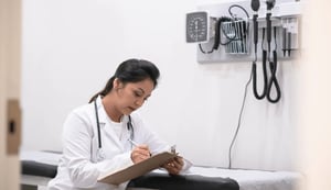 Latina Medical professional writing on clipboard